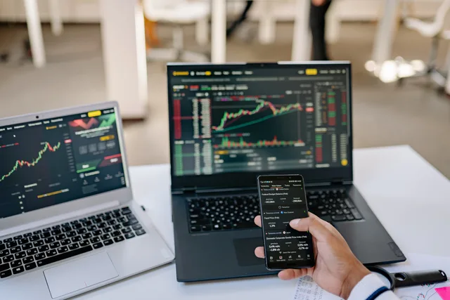 A professional tracks stock market trends using two laptops and a smartphone, showcasing digital finance tools. Finance creators: choosing a channel strategy that fits the task
